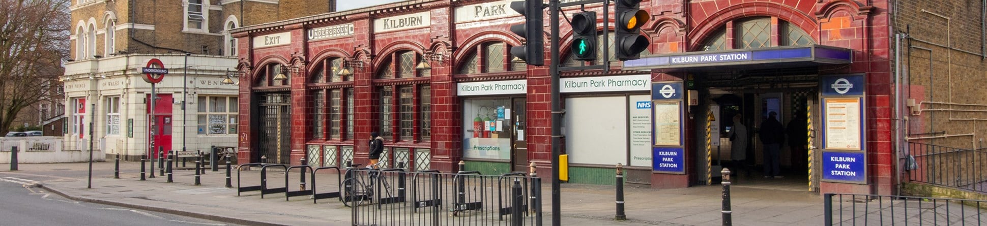 Red tiled tube station. Signs along the top of the building read (left to right):
Exit; Underground; Kilburn; Park; Underground; Entrance.