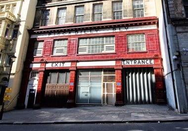 Red tiled station exterior. Signage reads: Piccadilly Rly - Exit - Entrance