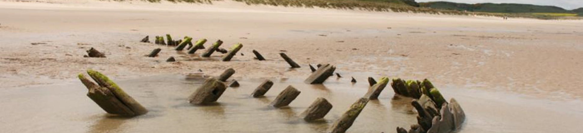 The wreck of a late 18th-century coastal sailing vessel on the beach below Bamburgh Castle, Northumberland, scheduled monument