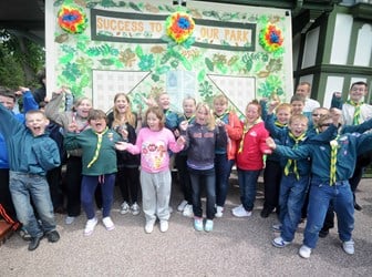 A group of young scouts celebrate in front of a poster which reads 'success to our park'