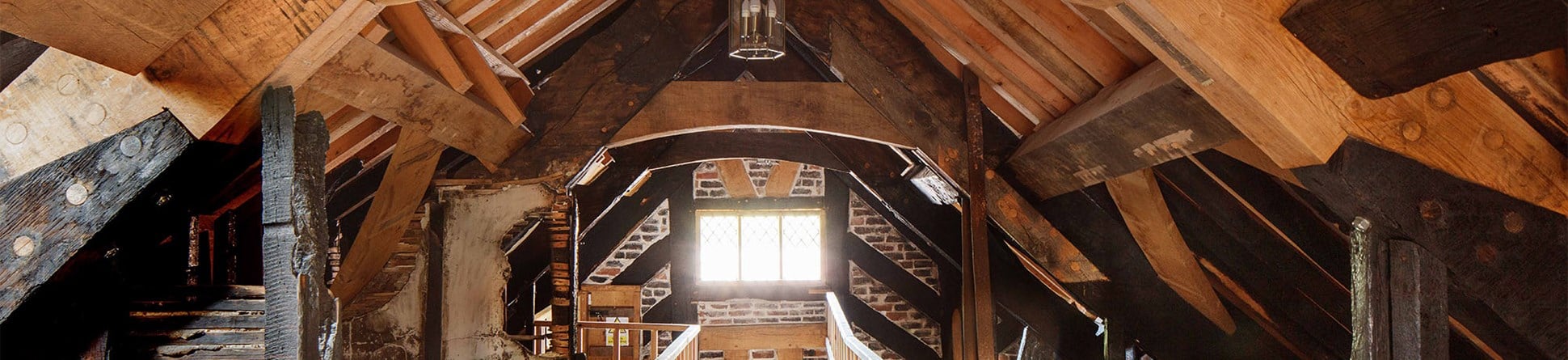 Wooden beams in a timber roof - some new, some blackened by fire.