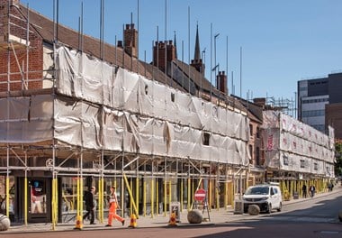 General view of the Burges, Coventry, viewed from north west. Most of the buildings are obscured by scaffolding and upper floors are also covered with tarpaulin.