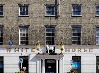 A front view of a white and grey brick hotel with a blue plaque. 