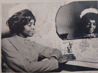 A black and white photo of a nurse posing by a mirror