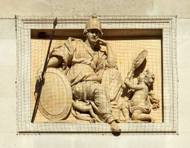 Statue of soldier seated and holding a spear.