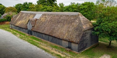 A weather-boarded aisled barn about 44m long and 11m wide. There is a gabled entrance in the centre of the north side. The thatched and half-hipped roof is of crown post construction with reversed assembly in the aisles.