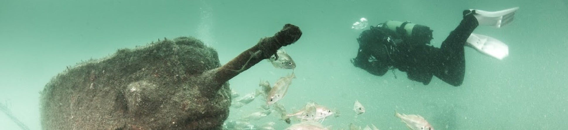 The submerged remains of a tank being recorded by a diver.