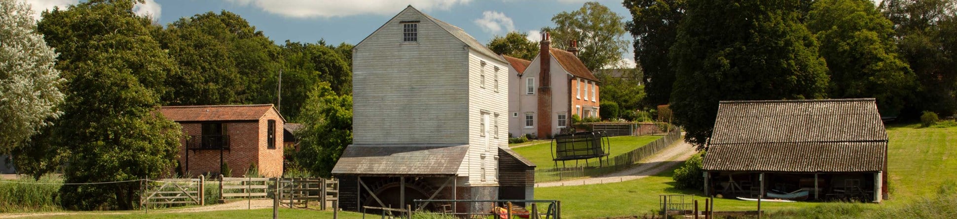 Mill buildings set on a hill with a lake in the foreground